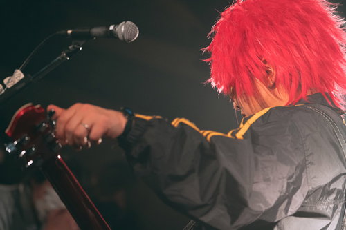 ステージでギターをチューニングするギタリストの背後姿