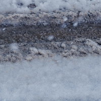 新雪と圧雪が層をなす雪道にくっきり残るタイヤ痕の写真