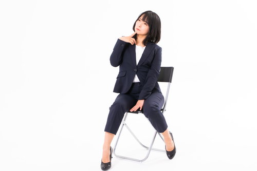 椅子に腰かけて疑問を抱く女性社員のビジネスポーズ
