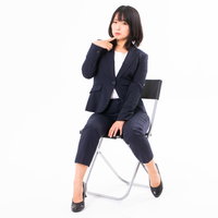 人差し指を顎に当てて思わせぶりな視線を送る女性社員の写真