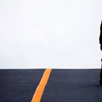 アスファルトの道路を歩く男性の足元と靴の写真
