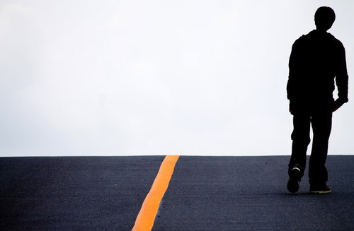 アスファルトの道路を歩く男性の足元と靴