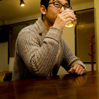 薄暗いバーでグラスを持つデザイナーの男性の写真