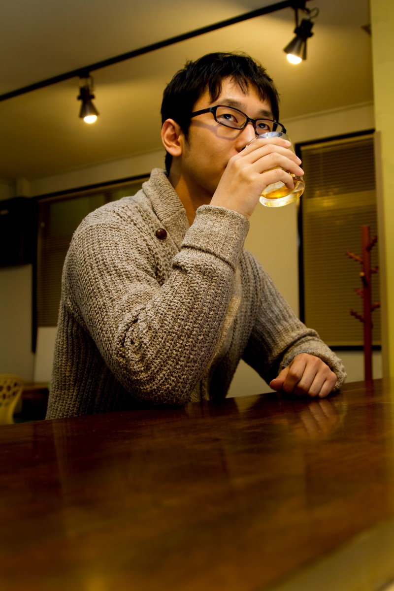 バーでグラスを持つ男性［モデル：大川竜弥］