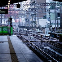 線路と架線が続く駅のホームからの風景の写真