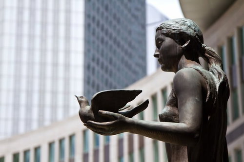 公園に立つ鳩を手に載せたブロンズ像