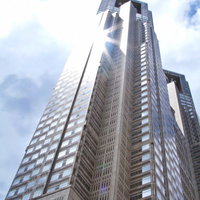 ガラスの外壁に日差しが反射して光る東京都庁の写真