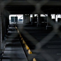 金網フェンス越しに見える誰もいない広い駐車場の写真