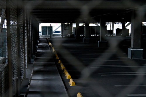 金網フェンス越しに見える誰もいない広い駐車場