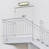 白い壁に緑の避難口サインがある非常階段の写真