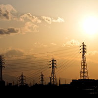 鉄塔と送電線が交差する夕焼けのオレンジの空の写真