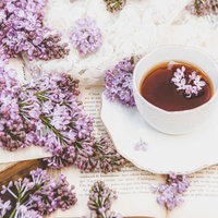 溢れんばかりのライラックとティーカップの紅茶の写真