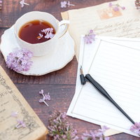 ティーカップに浮かぶライラックと白紙のレターセットの写真