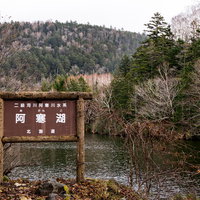 北海道・阿寒湖の湖畔に立つ木製の案内看板の写真