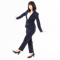 ヒールを履いて膝を曲げずに正しい姿勢で歩く女性社員の写真