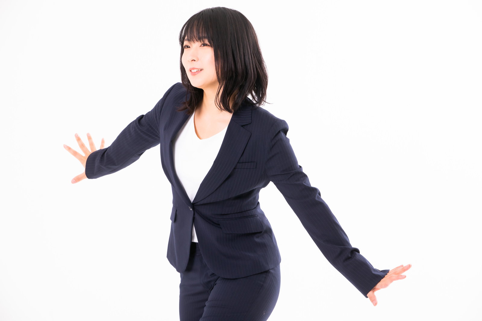 両手を広げてセーフのポーズをとる紺色スーツ姿の女性社員［モデル：にゃるる］