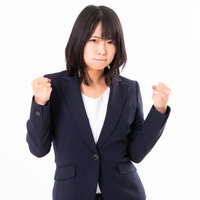 両手に力を込めるガッツポーズの女性社員のやる気満々の姿の写真