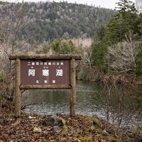 北海道・阿寒湖の湖畔に立つ木製の看板と秋の景観の写真