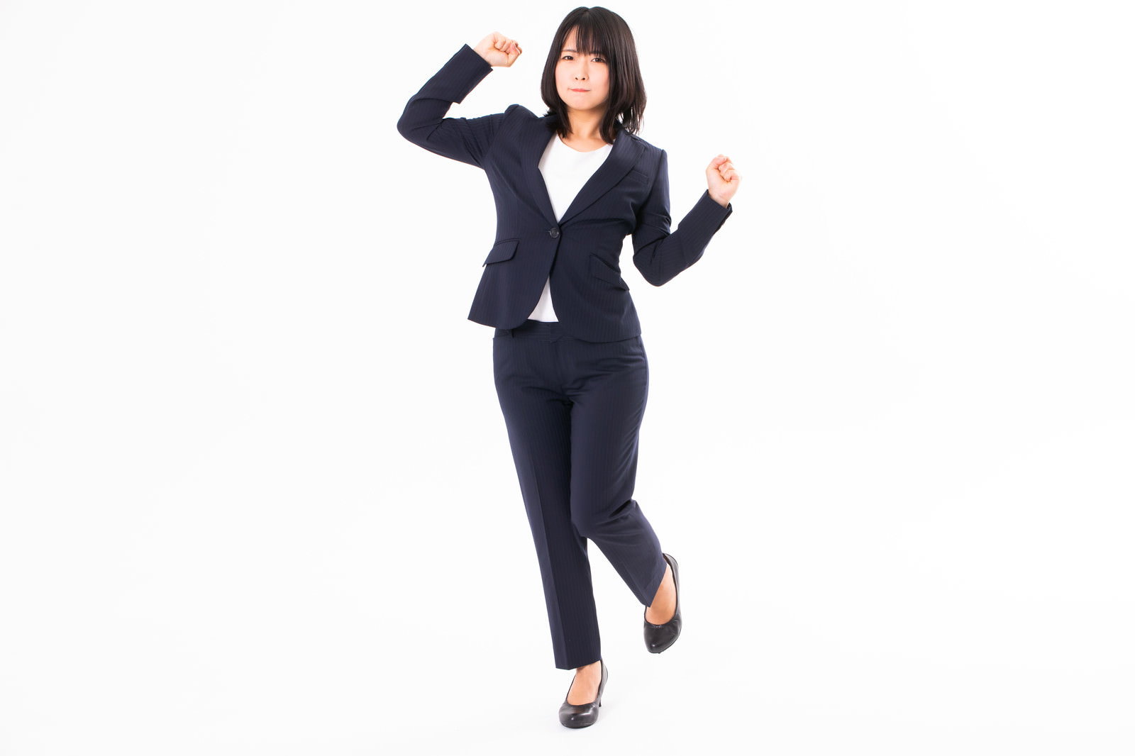 黒いスーツを着た女性が立ち上がりながら伸びをしている様子［モデル：にゃるる］