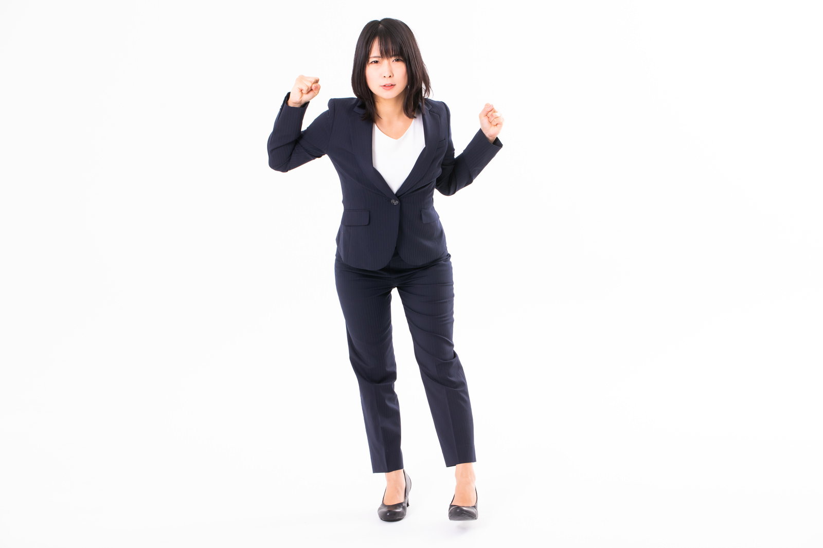 憤怒の表情で両手を腰に当て立つ紺色スーツの女性社員［モデル：にゃるる］