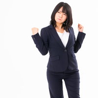 拳を握って怒りを我慢する女性社員のストレス表現の写真