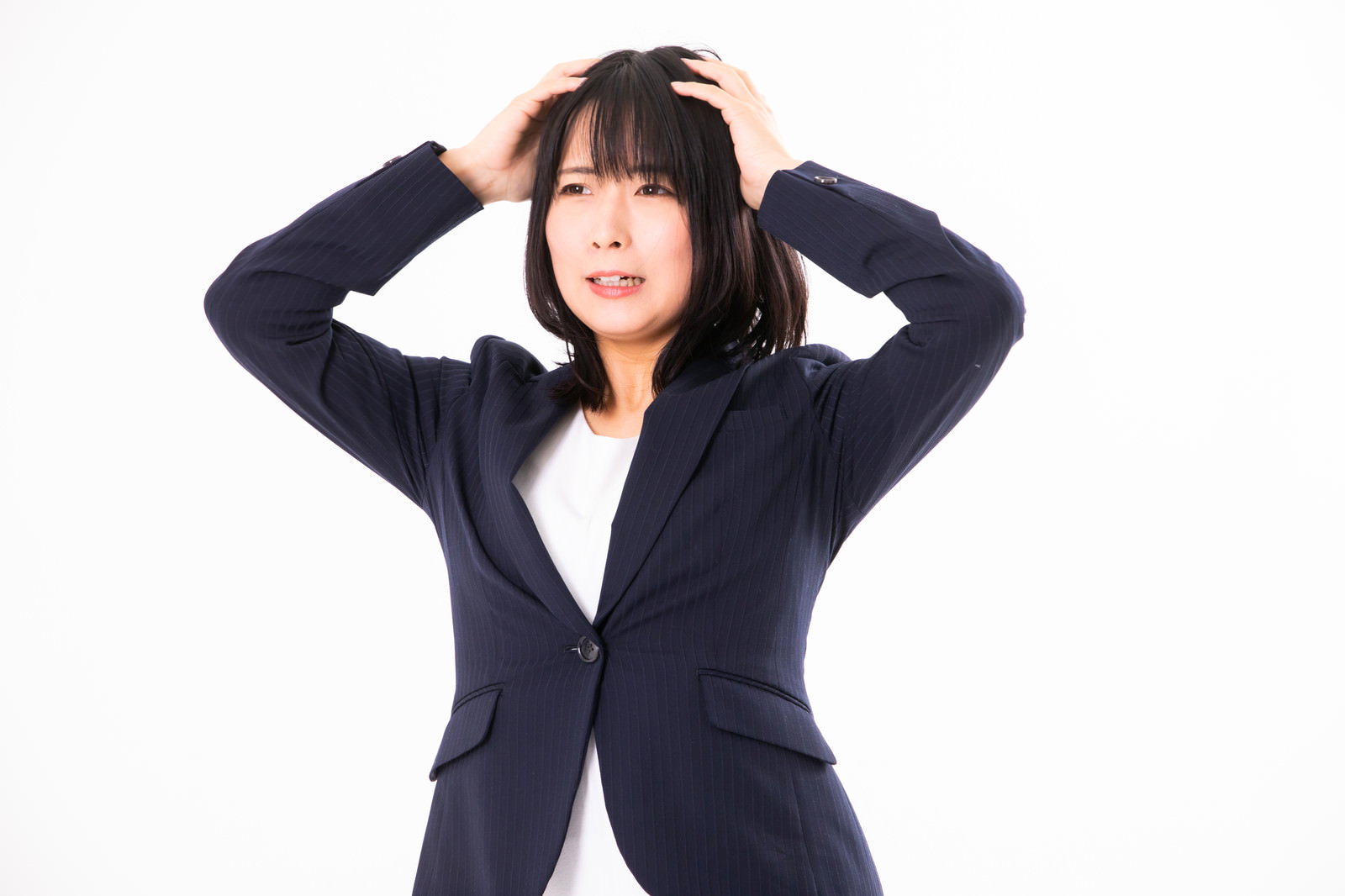 黒いスーツを着た女性が両手で頭を抱えて絶望している様子［モデル：にゃるる］