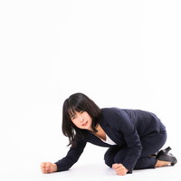 悔しくて床を叩く紺色のスーツ姿の女性社員の写真