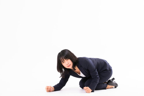悔しくて床を叩く紺色のスーツ姿の女性社員