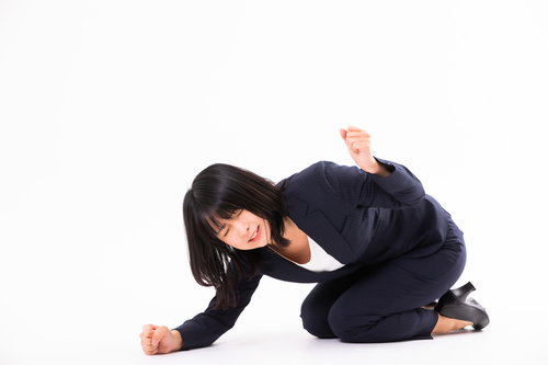 床を叩いて悔しがる女性社員の激しい仕草と怒りの感情表現