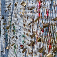 金属フェンスに複数括り付けられた錆びた南京錠の写真