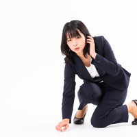 コンタクトを落とした際に膝をつく女性社員の写真