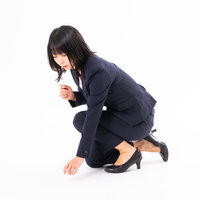 落とし物を見つけた女性の後ろ姿、膝をついて探すの写真