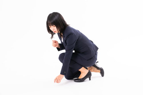 落とし物を見つけた女性の後ろ姿、膝をついて探す