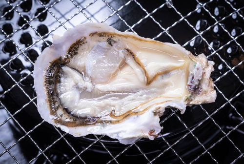 網焼きで調理される牡蠣の殻が開いた状態と貝柱