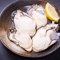 レモン添えの生ガキ盛り合わせ、陶板の器に盛り付けた新鮮な牡蠣の写真