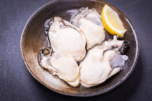 レモン添えの生ガキ盛り合わせ、陶板の器に盛り付けた新鮮な牡蠣