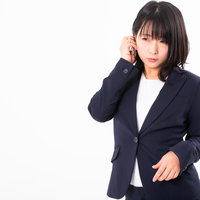 紺色のリクルートスーツで髪を耳にかける女性社員の写真