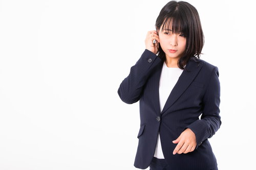 紺色のリクルートスーツで髪を耳にかける女性社員