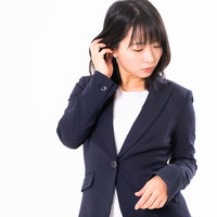 紺色スーツの女性、髪を耳にかけてピアスが見え隠れするの写真