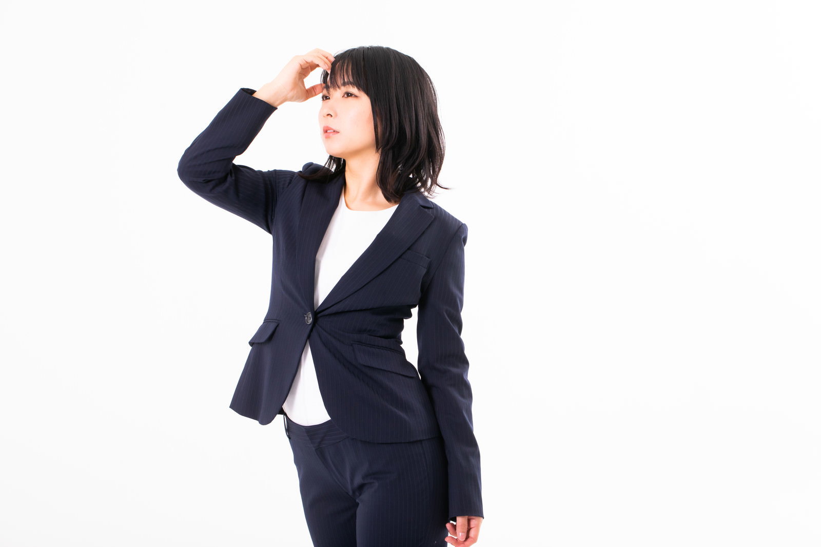 手を額にかざして遠くを見つめる黒いスーツを着た女性［モデル：にゃるる］
