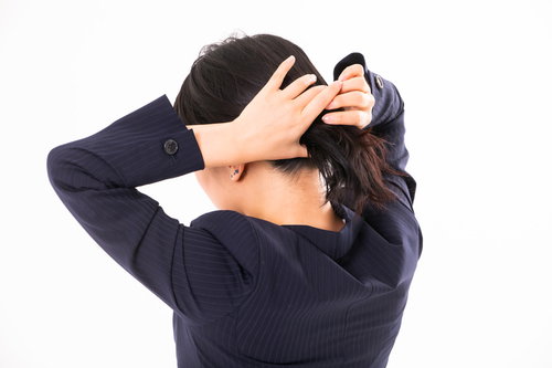 紺色のスーツを着て後ろ髪をひとつ結びする女性