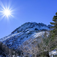 快晴の青空の下、光芒が輝く日光白根山山頂方面の写真