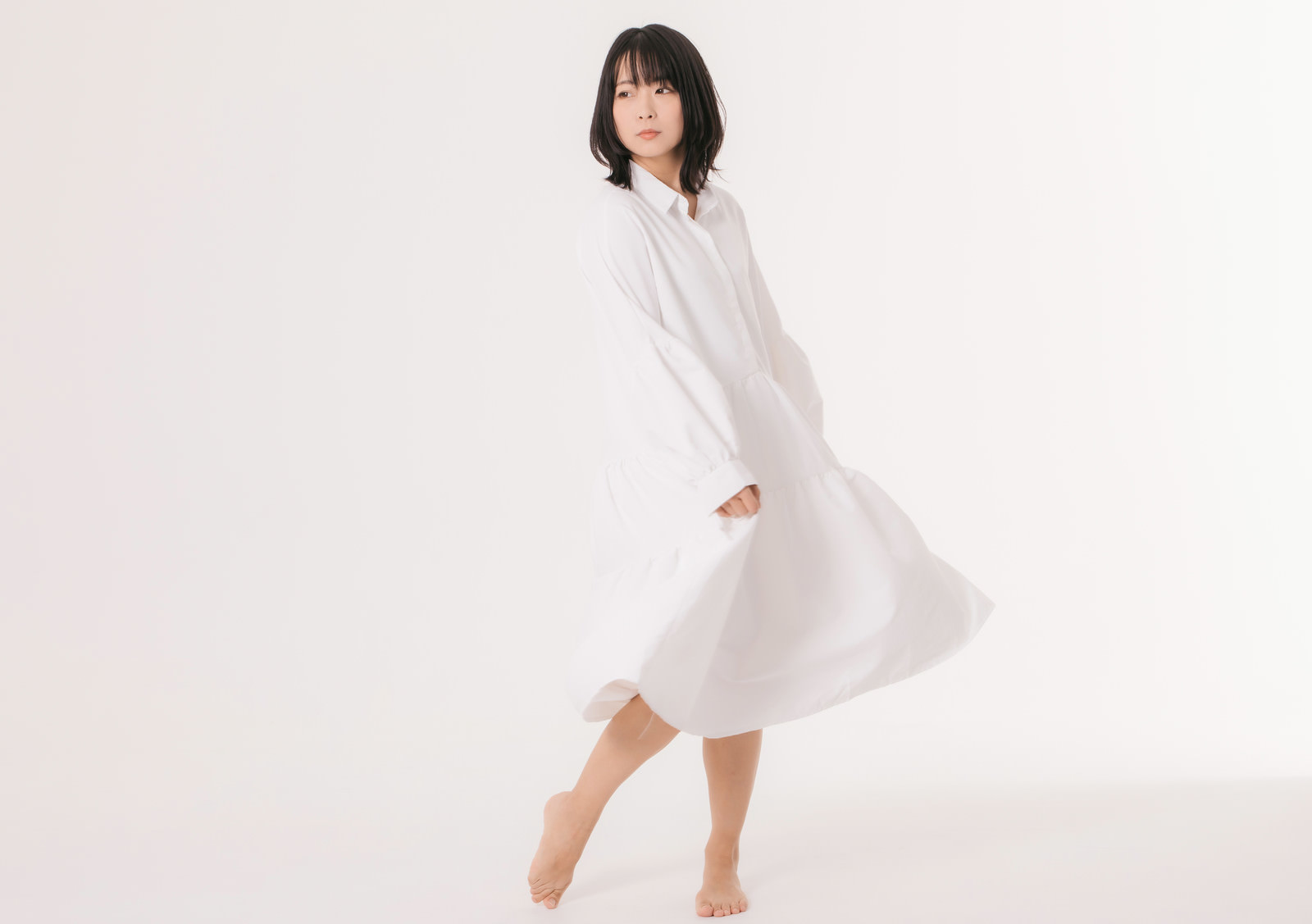 Woman posing with her hair pushed up, wearing a white dress