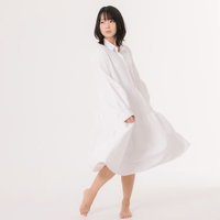 白いワンピースを着て髪をかき上げる爽やかなポーズの女性の写真