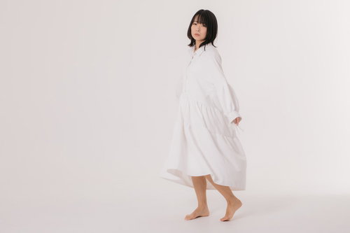 寂しげな表情で見つめる白いワンピースの女性