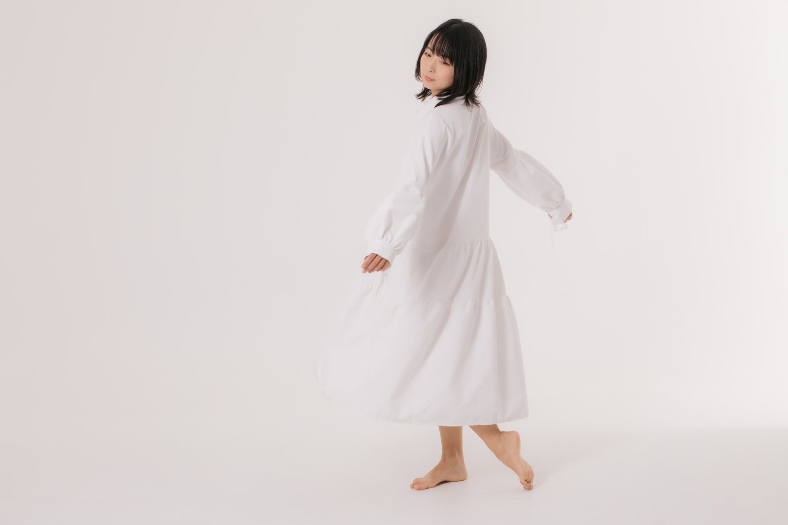 白いワンピースを着て振り返るポーズをとる女性モデル［モデル：にゃるる］