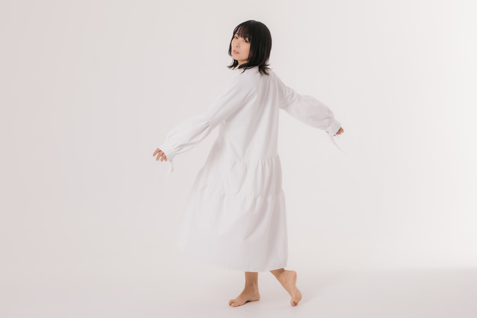 白いワンピースを着て振り返るポーズをとる女性モデル［モデル：にゃるる］