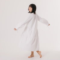 少し大きめの白いワンピを着て振り返る女性モデルの写真