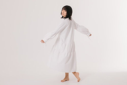 少し大きめの白いワンピを着て振り返る女性モデル