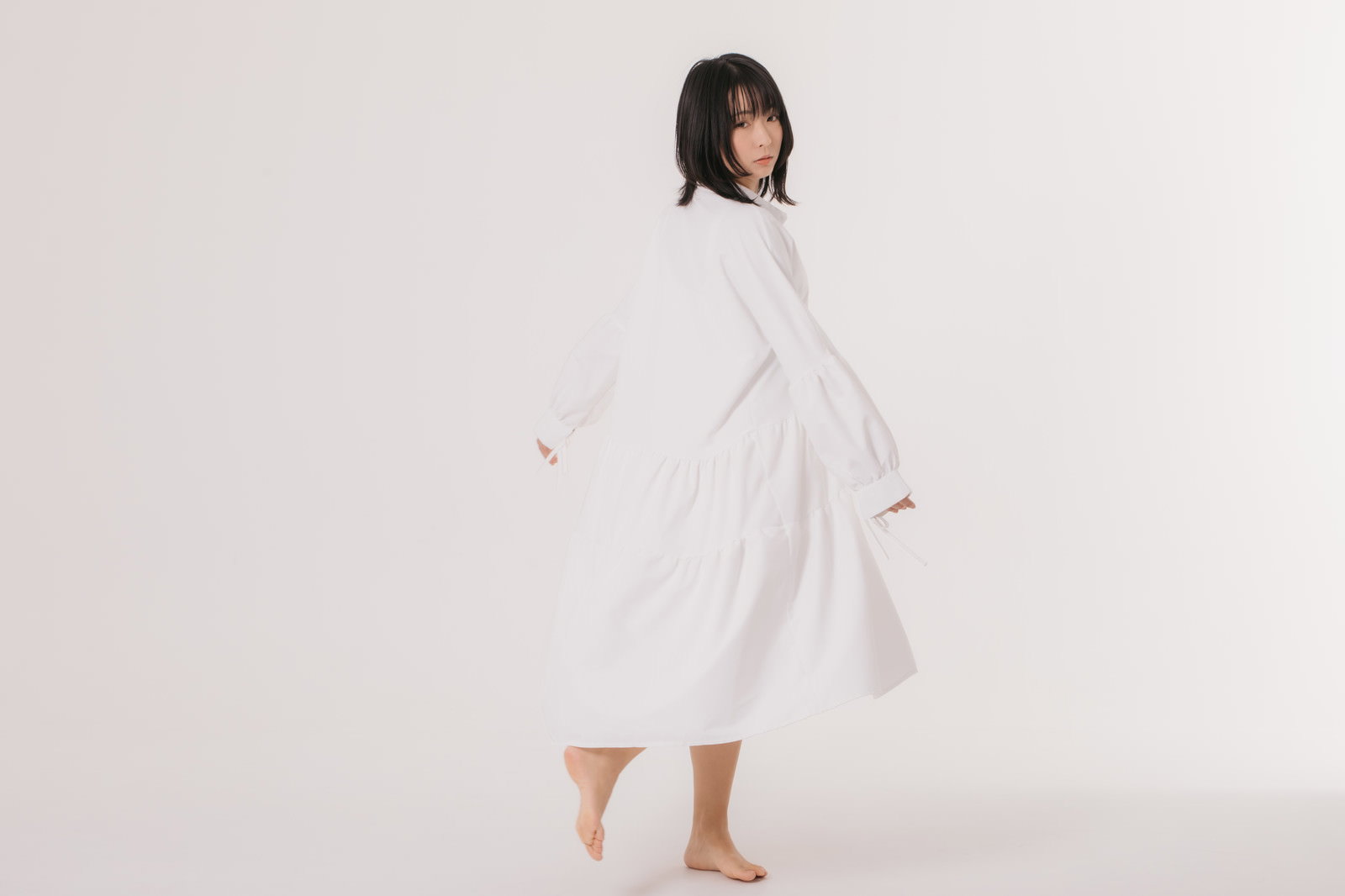 白いワンピースを試着して振り返るポーズをとる女性［モデル：にゃるる］